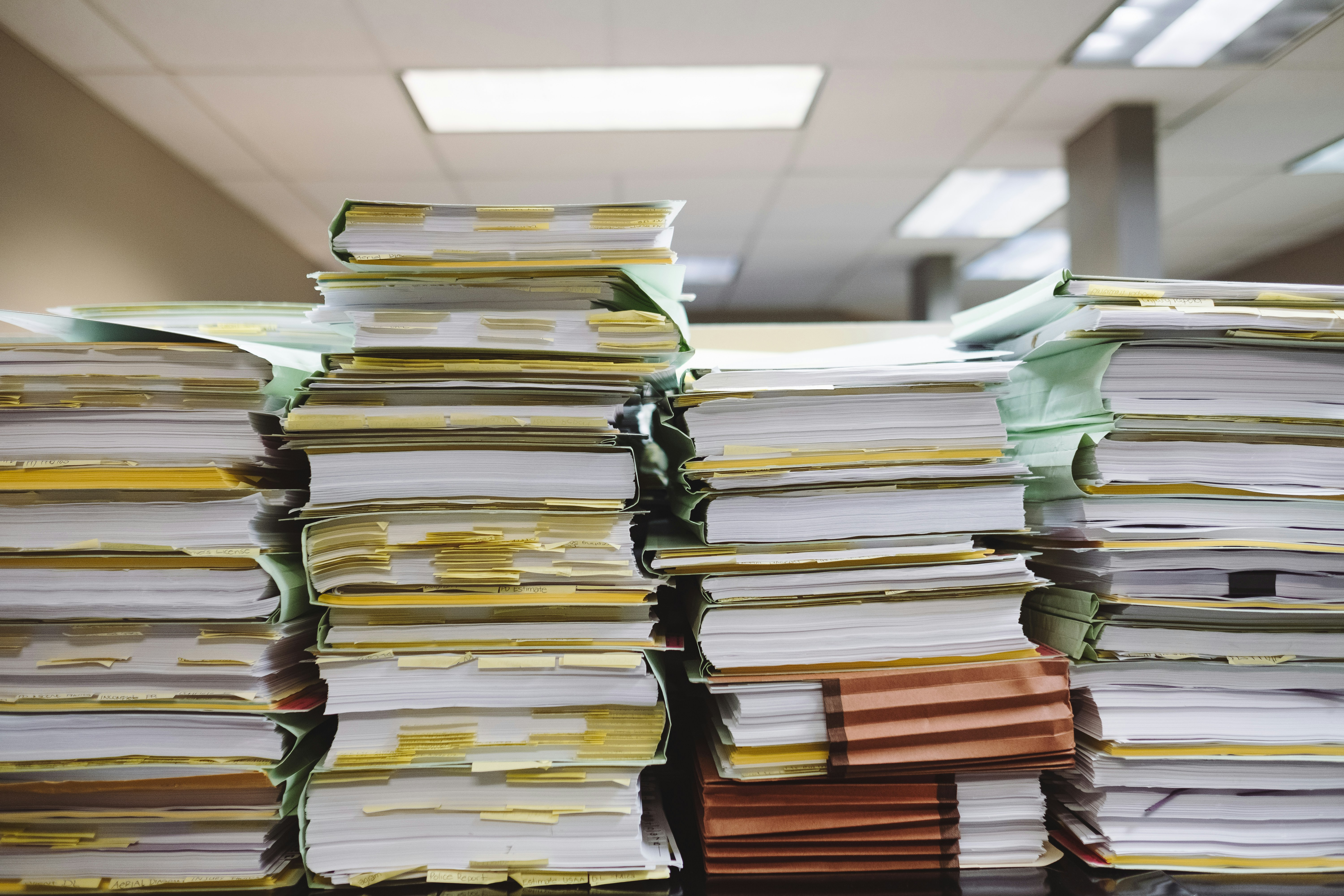Photograph of several rows of documents piled high in an office.